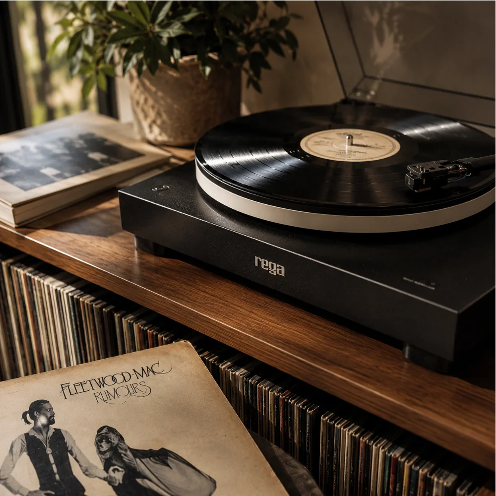 A vinyl record playing on a turntable above shelves of albums